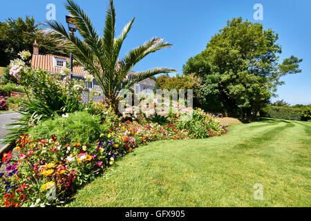 Ferienhaus Blumenbeeten und Rasen gegen blauen Himmel Stockfoto