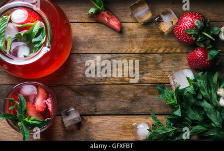 Hausgemachte Erdbeer Minze Limonade serviert mit frischen Beeren und Eis über hölzerne Hintergrund, Draufsicht, Textfreiraum Stockfoto