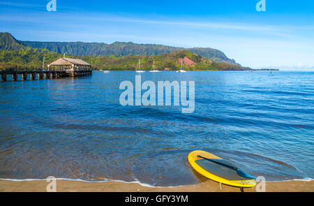 Paddleboard am Ufer des Hanalei Bay in der Nähe von Hanalei Pier, mit Mt. Makana, genannt Bali Hai in Ferne aufstehen Stockfoto