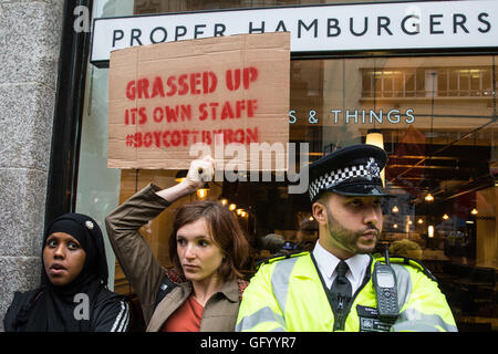 London, UK. 29. Juli 2016. Ein Demonstrant hält ein Schild ruft zum Boykott von Byron-Hamburger-Kette außerhalb seiner Niederlassung in Holborn bei einem Protest gegen die Art und Weise, in das Management der Hamburger Kette angeordnet, Gesundheit und Sicherheit treffen zu der Verhaftung und Deportation von vielen Mitgliedern des Personals. Bildnachweis: Mark Kerrison/Alamy Live-Nachrichten Stockfoto