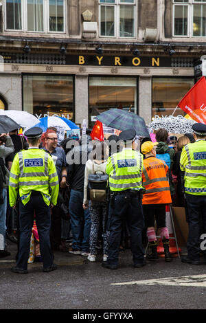 London, UK. 29. Juli 2016. Polizei überwachen Hunderte von Anhängern der Organisationen einschließlich der Gewerkschaften, Wohlfahrtsverbände und Menschenrechtsgruppen protestieren außerhalb ein Zweig der Byron in Holborn gegen die Art und Weise in die Verwaltung der Hamburger Kette angeordnet, Gesundheit und Sicherheit treffen zu der Verhaftung und Deportation von vielen Mitgliedern des Personals. Bildnachweis: Mark Kerrison/Alamy Live-Nachrichten Stockfoto