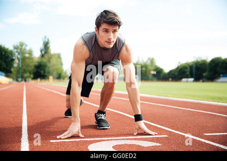 Porträt des jungen muskulöse Athleten am Anfang des Laufbandes im Stadion Stockfoto