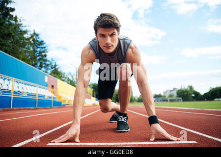 Young konzentrierte sich Sportler mit dem Sprint beginnen und auf der Suche in die Kamera Stockfoto