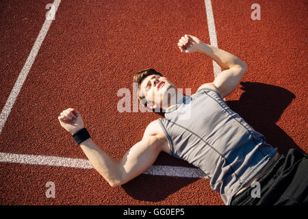 Fitness Jüngling Handauflegen Laufstrecke nach dem harten Training im Stadion Stockfoto