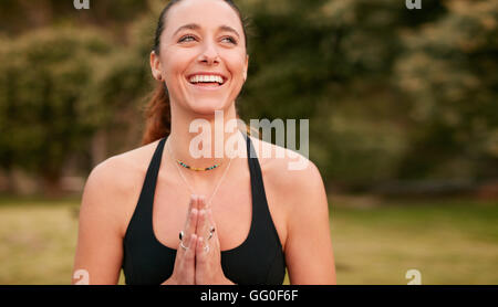 Porträt einer selbstbewussten, sportlichen Frau, die Yoga praktiziert, blickt weg und lächelt. Fitness-Frau trägt Sport-BH mit den Händen Jo Stockfoto