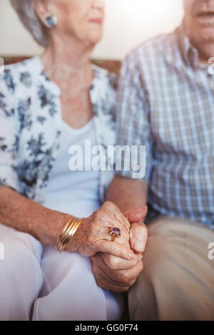 Schuss von älteres paar Hand in Hand zusammen sitzen abgeschnitten. Konzentrieren Sie sich auf Händen. Stockfoto
