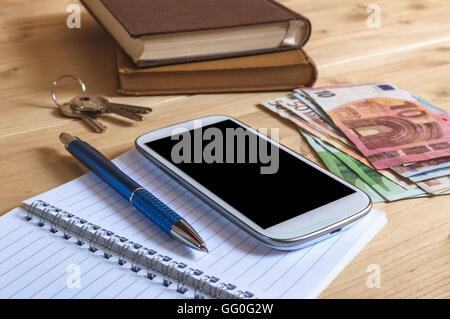 Still-Leben Foto Smartphone, Notebook, Buch, Stift, Geld und Schlüssel auf Holztisch. Selektiven Fokus. Stockfoto