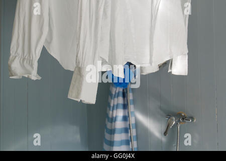 Weißes Hemd zum Trocknen auf eine Vorhangschiene Dusche im Badezimmer aufgehängt. Stockfoto