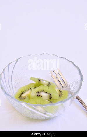 in Scheiben geschnittenen Kiwis in einer Schüssel mit Silber Gabel auf weißem Hintergrund, Makro, Nahaufnahme, vertikal, Raum für Text, Textfreiraum, Stockfoto