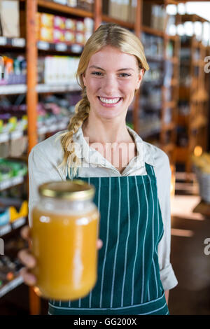 Weibliche Personal halten Glas Honig im Supermarkt Stockfoto