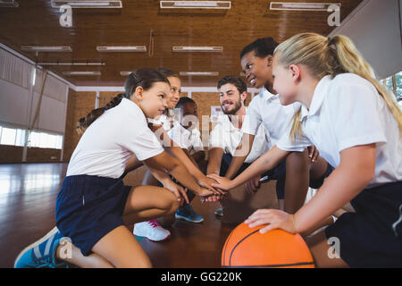 Sport Lehrer und Schule Kinder bilden Hand Stack in Basketballplatz Stockfoto