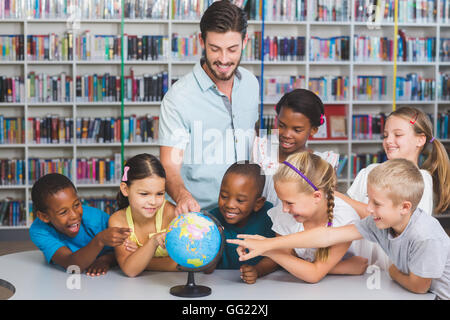 Schüler und Lehrer im Globe in Bibliothek suchen Stockfoto