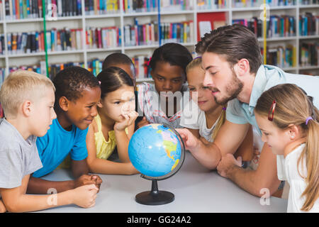 Schüler und Lehrer im Globe in Bibliothek suchen Stockfoto