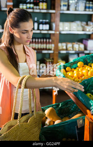 Frau mit ihr Handy beim Kauf von Obst im organischen Bereich Stockfoto