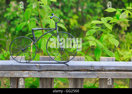Ein wenig Fahrrad Ornament aus Schmiedeeisen auf einem hölzernen Garten Zaun gemacht. Stockfoto