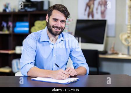 Physiotherapeuten, die auf einem Klemmbrett schreiben Stockfoto