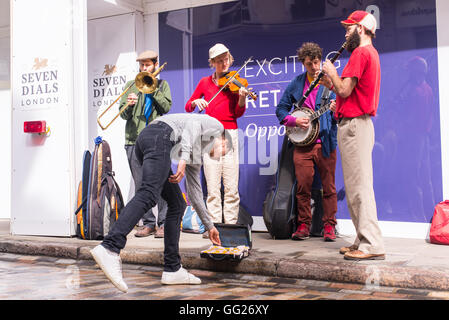 Mann verlassen ein Angebot zu einem Quartett Brass Band während der Seven Dials Street Festival, London Straßenmusik, Großbritannien Stockfoto