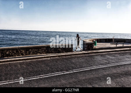 Ein Mann, der allein auf der Straße am Meer entlang läuft, Rethymno, Kreta, Griechenland Stockfoto