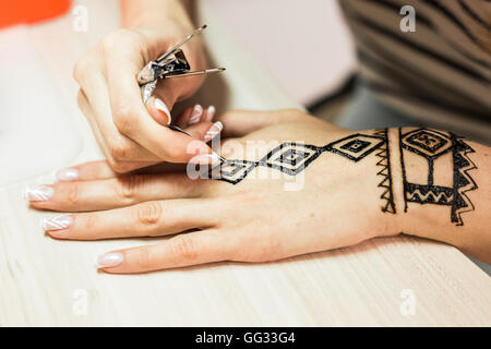 Künstler, die Anwendung von Henna-Tattoo auf Frauen Hände. Mehndi ist die traditionelle indische dekorative Kunst. Close-up Stockfoto