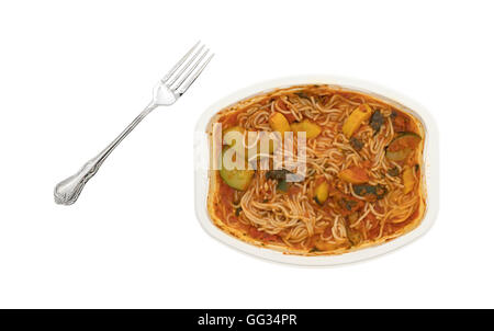 Ein warmes Abendessen der TV Angel Hair Pasta mit Zucchini und Spinat mit einer Gabel seitlich in eine mikrowellengeeignete Schale auf eine weiße Rückseite Stockfoto