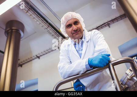 Lächelnde Hersteller stützte sich auf Rohr in der Brauerei Stockfoto