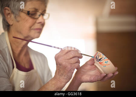 Nahaufnahme von weiblichen Potter Malerei auf Schale Stockfoto