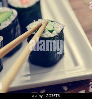 Nahaufnahme von einem weißen Keramik Tablett mit einigen verschiedenen Makizushi, gefüllt mit Avocado und Lachs Stockfoto