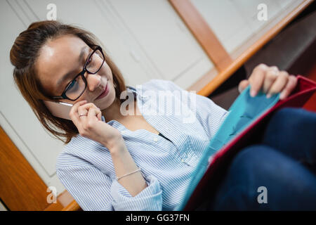 Junge Frau am Handy in Umkleidekabine Stockfoto