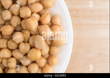 Draufsicht enger auf einem weißen Teller mit einer Portion Bio Kichererbsen auf einem Holztisch. Stockfoto