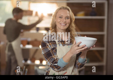 Lächelnde weibliche Potter Überprüfung Schüssel in Keramikwerkstatt Stockfoto