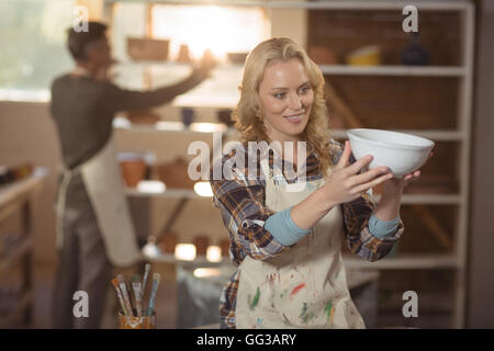 Weibliche Potter Überprüfung Schüssel in Keramikwerkstatt Stockfoto