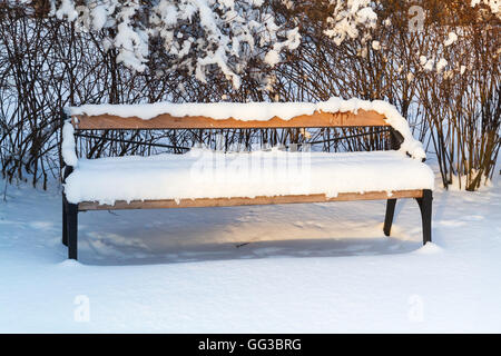 Outdoor-Holzbank bedeckt mit Schnee im Winter Park. Turku, Finnland Stockfoto