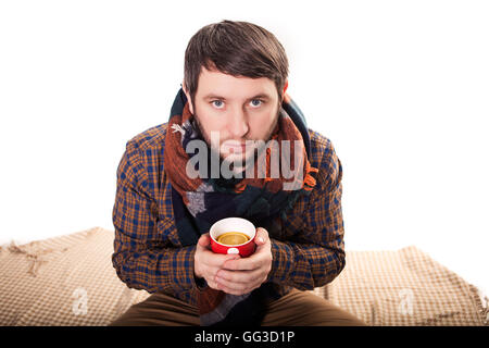 Hübscher junger Mann in Winterkleidung hält eine Tasse heißen Tee. Stockfoto