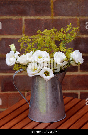 Blumenarrangement von weißen Prärie Enziane und zarten Alchemilla Mollis im Vintage Metall Krug Stockfoto