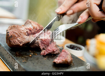 Filetsteak wird gekocht und geschnitten auf einem heißen Stein in einem restaurant Stockfoto