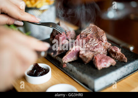 Rib-Eye Steak wird gekocht und geschnitten auf einem heißen Stein in einem restaurant Stockfoto