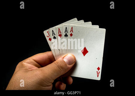 Hand, die Pokerkarten, um ein Poker Asse auf schwarzem Hintergrund bilden Stockfoto