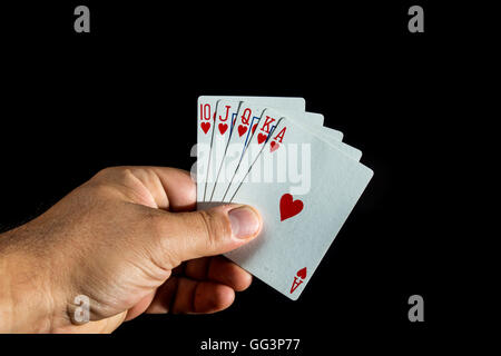 Hand, die Pokerkarten, um einen Royal Flush auf schwarzem Hintergrund bilden Stockfoto