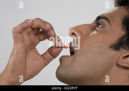 Mann, der eine Pille in den Mund Stockfoto