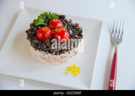 Russischer Salat mit Cherry-Tomaten, schwarzen Oliven, Petersilie und Perlen von Olivenöl. Stockfoto