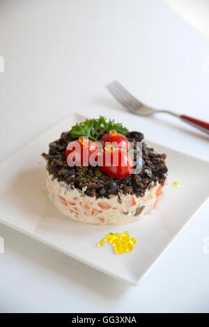 Russischer Salat mit Cherry-Tomaten, schwarzen Oliven, Petersilie und Perlen von Olivenöl. Stockfoto