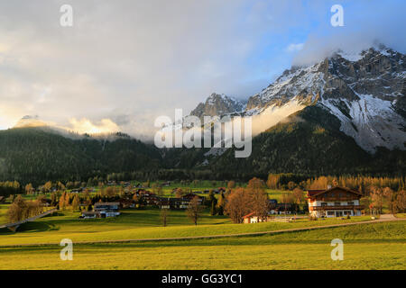 Das malerische Dorf am Fuße der Alpengipfel an einem Frühlingstag, wunderschön bunten Wiesen, die Abendsonne, Österreich Stockfoto