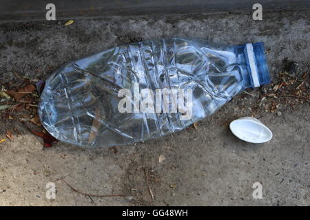 Zerkleinert Kunststoff Flasche auf den Boden. Gepresstem Kunststoff Flasche auf dem Land. Einwegflasche entfernt auf den Boden geworfen, auf trockenem fallen lässt. Stockfoto