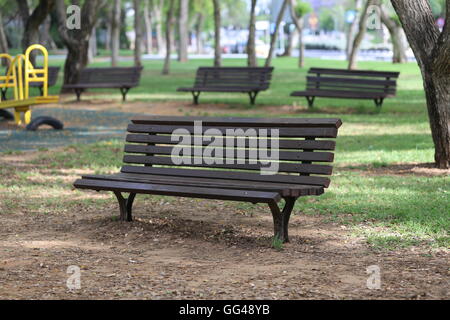 Parkbänke. Öffentliche Parkbänke in den schattigen Hain. Hölzerne Bänke im Park in der Nähe von Spielplatz Spielzeug. Stockfoto