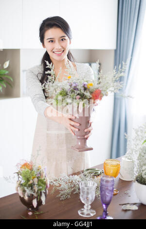 Junge Chinesin, die Vermittlung von Blumen zu Hause Stockfoto