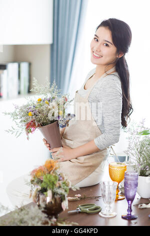 Junge Chinesin, die Vermittlung von Blumen zu Hause Stockfoto