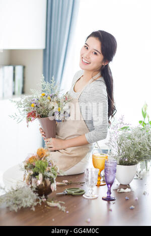Junge Chinesin, die Vermittlung von Blumen zu Hause Stockfoto