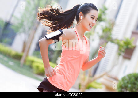 Junge Chinesin Joggen und Musik hören Stockfoto