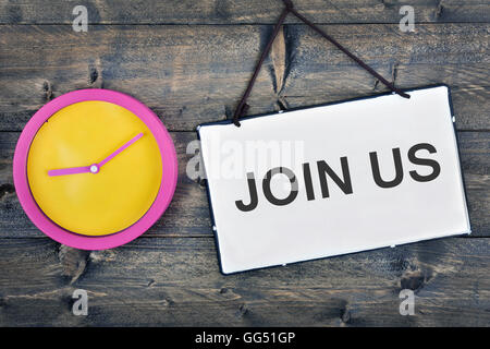 Begleiten Sie uns Zeichen und Uhr auf Holztisch Stockfoto