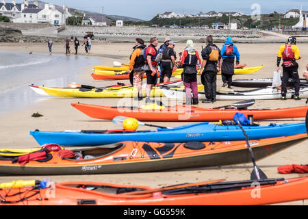 Eine Gruppe von Meer Kajakfahrer mit ihren Booten am Strand von Treaddur Bay, Anglesey, Wales Stockfoto